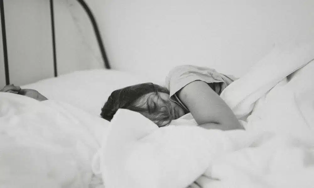 grayscale photo of sleeping woman lying on bed