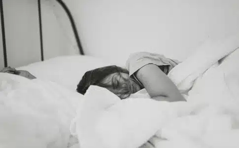 grayscale photo of sleeping woman lying on bed