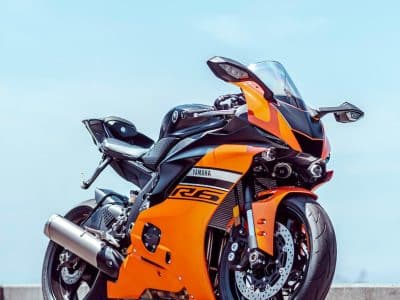 orange and black sports bike parked on gray concrete pavement during daytime