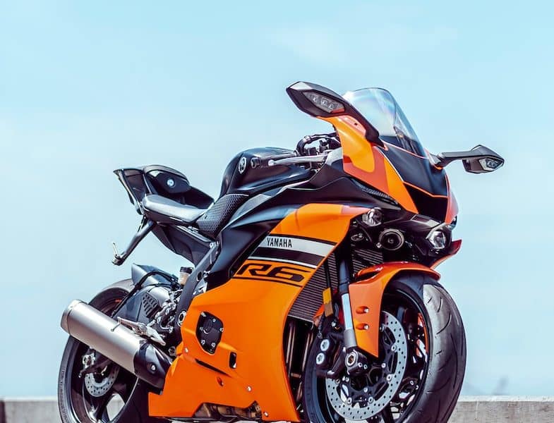 orange and black sports bike parked on gray concrete pavement during daytime