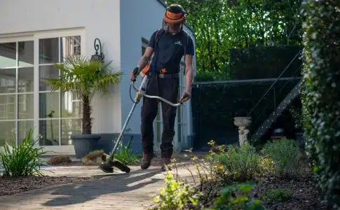 man in black t-shirt and blue denim jeans holding shovel